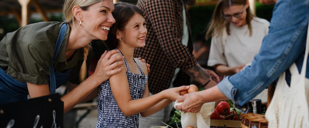 mom and daughter buying eggs from farmers market